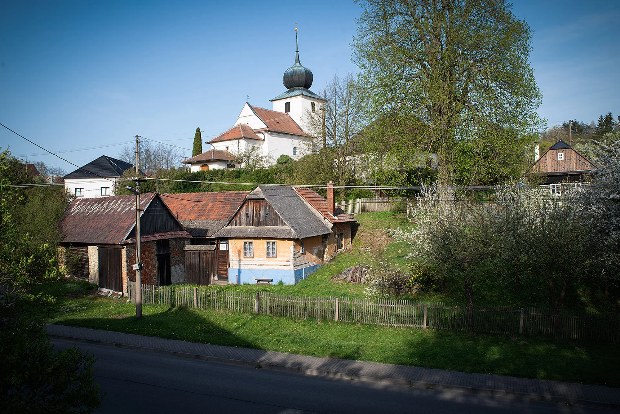 Kostel svaté Maří Magdalény od cesty s roubenkou